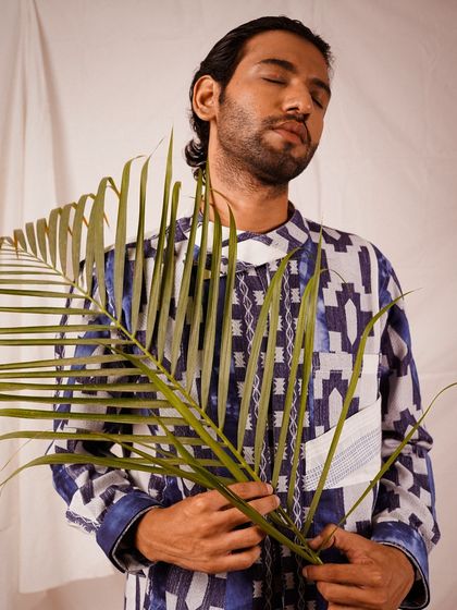 Using a simple prop like a palm leaf can add a natural, artistic element to a studio shoot. This pose feels serene and thoughtful, adding another layer to the character of the portrait.