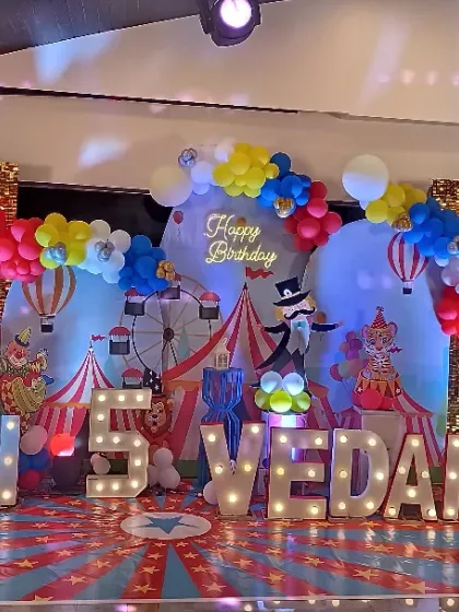 A wide view of the vibrant carnival stage setup. The design includes a custom printed floor, multiple character cutouts, and a gold shimmer wall for extra sparkle.
