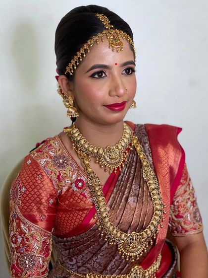 The bride's complete look, showcasing the beautiful harmony between her makeup, jewellery, and traditional red and gold saree.