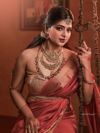 A regal portrait series inspired by the queens of Tulunadu. The model is adorned in a stunning red saree and antique-style jewelry, captured in a heritage location to enhance the royal theme.