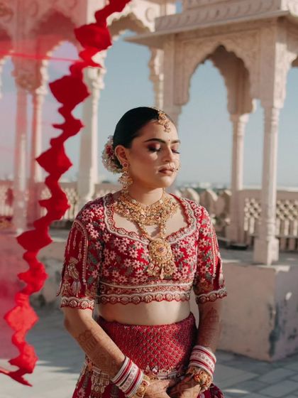 The bride, with her eyes closed, basks in the sun, a red smoke effect adding a touch of artistic flair to the portrait.