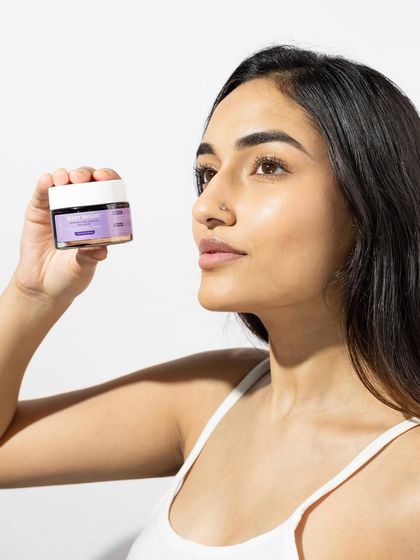 A clean and simple model shot that puts the focus on the product. The model's gaze is directed towards the jar, drawing the viewer's attention to it, while her clear skin reinforces the product's promise.