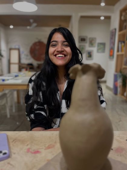 A candid shot of a participant smiling proudly behind her freshly sculpted clay vase. We love capturing these moments of creative accomplishment.