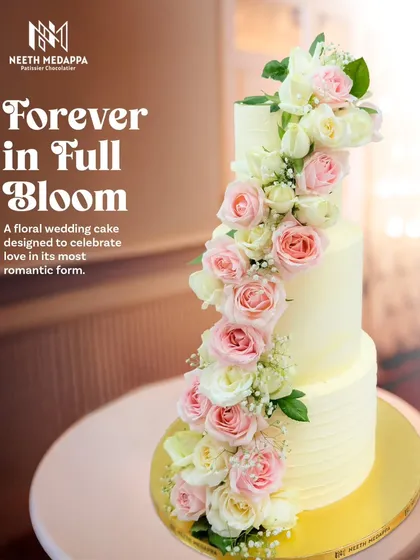 A wedding cake that feels like a love poem. This three-tiered creation features a stunning cascade of fresh pink and white roses, creating a look of timeless romance and pure elegance. It's a classic design that's always in bloom.