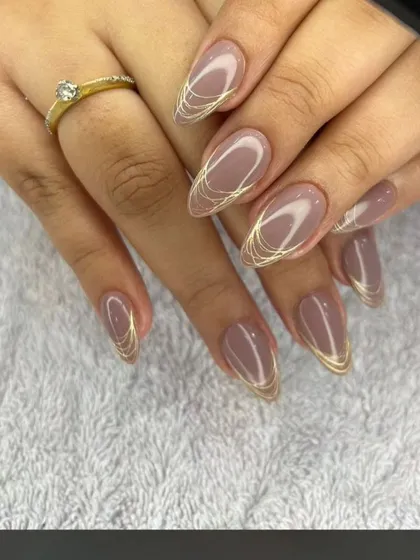 A sophisticated nude set with delicate, swirling gold line art on long, almond-shaped nails.