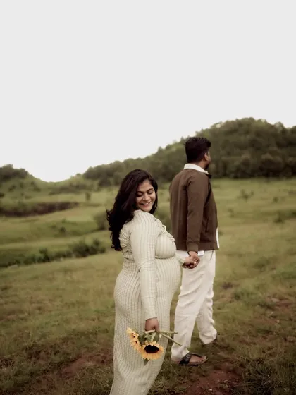 A classic "follow me" style shot. She looks back with a warm smile while leading him by the hand, symbolizing their journey into parenthood together.
