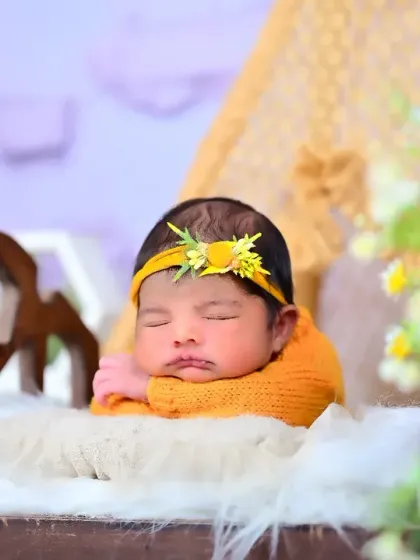 A newborn sleeping peacefully on a tiny bed prop. The soft yellow tones and floral elements create a warm and gentle image.