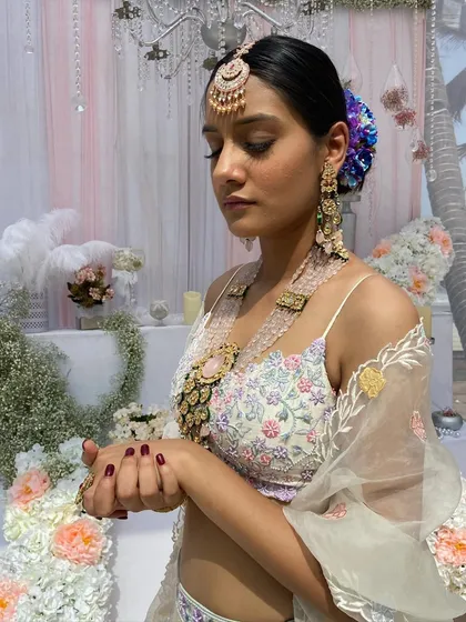 A profile shot of the bride, where the floral bun adds a beautiful pop of color against her pastel lehenga.