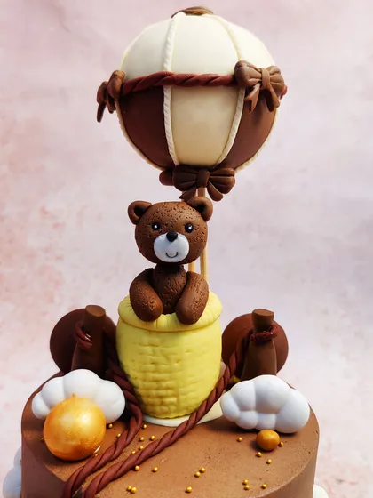 A close-up of our Brown Teddy Bear Cake, showing the adorable bear in a hot air balloon basket, ready for an adventure in the clouds.