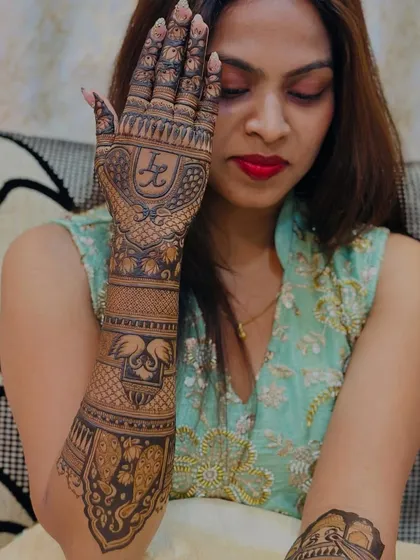 A bride showcasing one full arm of her mehendi, which features her initials, swans, and elephants.