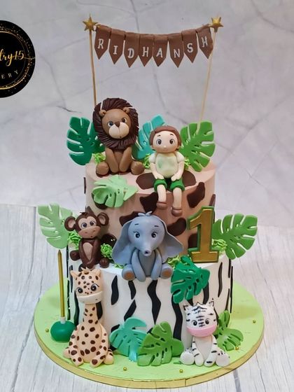 A fun 3kg two-tier jungle-themed cake for a first birthday. This mixed fruit cake features animal print designs and a variety of fondant animals.