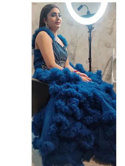 A client seated in a royal blue ruffled gown. The sheer volume of the ruffles creates a very dramatic and high-fashion look.