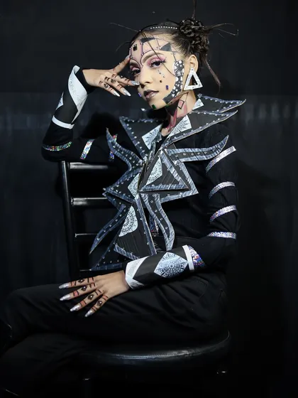 An avant-garde look with geometric patterns and a structured, futuristic collar. This teaches principles of design and applying them to makeup.