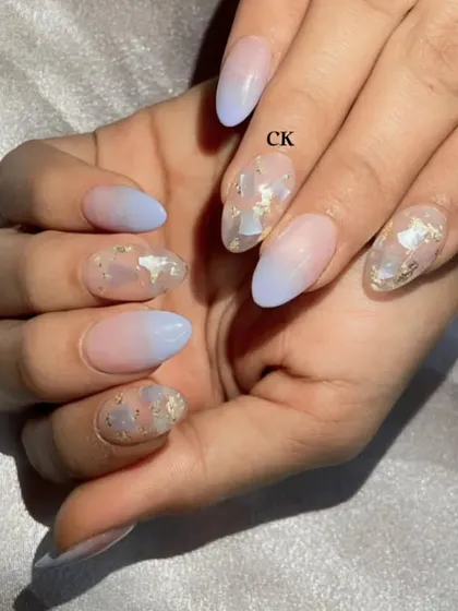 A close-up of the blue ombré and seashell fragment nails. This is a beautiful and serene design, perfect for a vacation.