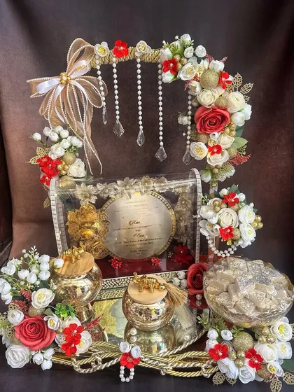 The first wedding invitation sets the tone for the entire celebration. I designed this royal 'first card' platter to be a grand statement, combining traditional elements with elegant red and gold floral arrangements to give the families a truly special moment.