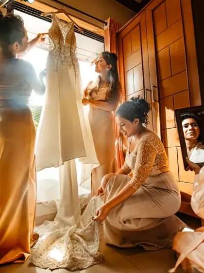 The final moments before she walks down the aisle. The warm morning light, the bridesmaids helping with the dress, the bride's reflection catching a glimpse. This is the build-up, the quiet story before the main event.