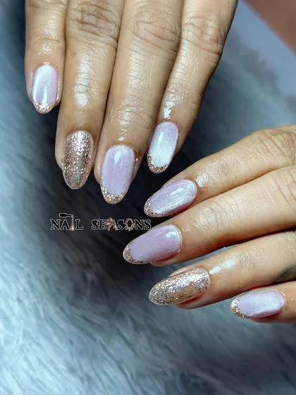 A soft lilac cat eye manicure with gold glitter tips and accent nails.
