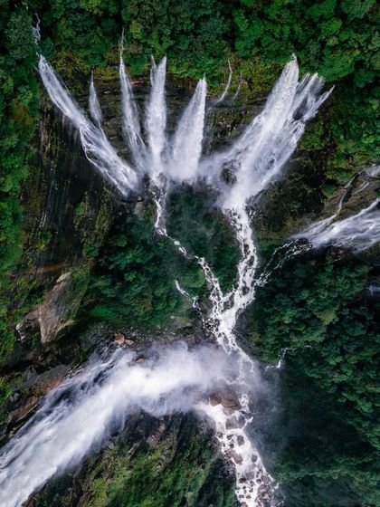 A breathtaking top-down view of the Seven Sisters Falls, resembling a hand of water spreading across the green earth.