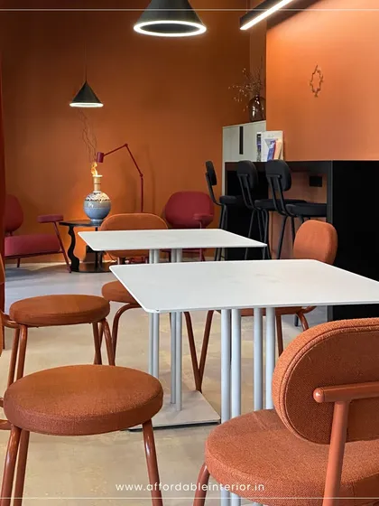 This warm and inviting cafe interior uses a terracotta color palette and modern furniture to create a memorable, "Instagram-worthy" customer experience. We focus on designing commercial spaces that are both aesthetic and functional.