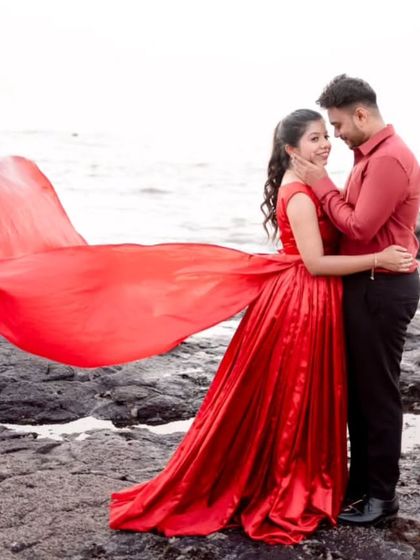 This shot captures the loving gaze between the couple, with the flowing red gown adding a touch of drama and color to the rocky seaside. It's all about capturing the emotion.