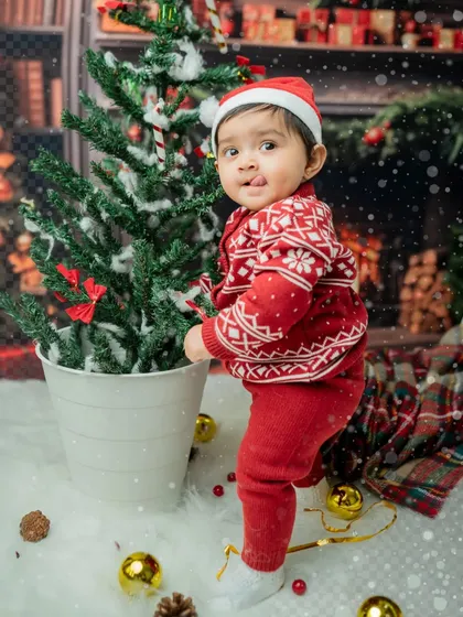 This little one is curiously investigating the mini Christmas tree, a perfect candid moment.