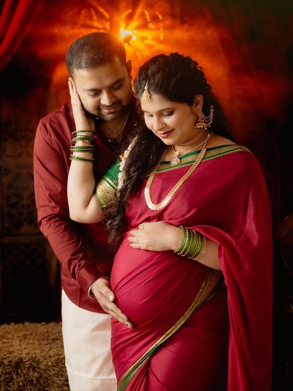 A close-up couple portrait filled with warmth and affection. The partner gently touches the mom-to-be's face as they both look down at the baby bump.