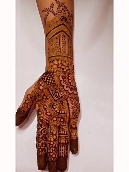 A detailed bridal design featuring a jharokha or palace window motif on the back of the hand. This is a great way to add a touch of royal architecture to your mehendi.