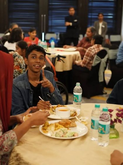 A young guest smiles while enjoying a delicious meal at our event for the Spastic Society. Creating moments of joy for our community is what matters most.