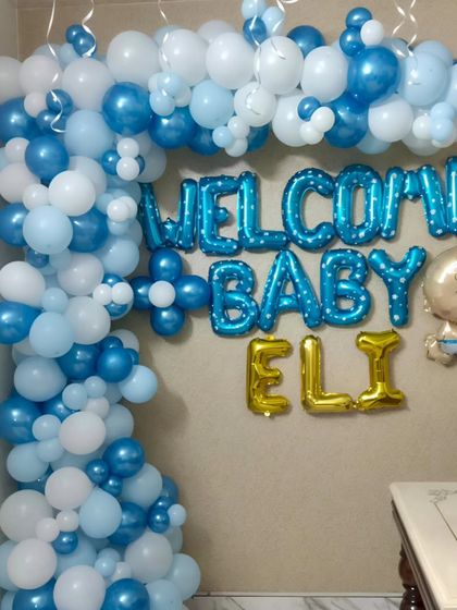 This detailed shot shows the organic balloon garland we created for baby Eli's welcome home party. The mix of different sized balloons in metallic blue, pastel blue, and white adds texture and depth to the overall design.