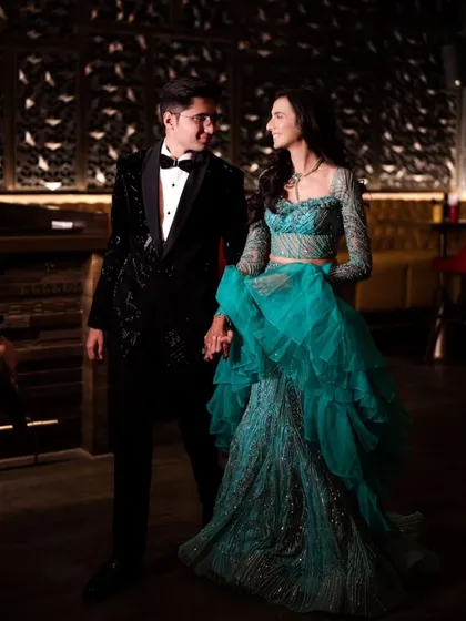 A full-length shot of the couple, hand in hand, ready for their cocktail evening. The bride's stunning teal gown and the groom's classic tuxedo create a look of pure sophistication.