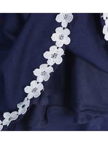 A detail shot of the floral lace trim on the hem of a navy blue baby frock.