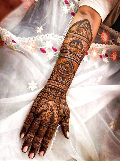 A single-arm view of a dense bridal mehandi, showcasing swans and jali (lattice) work.