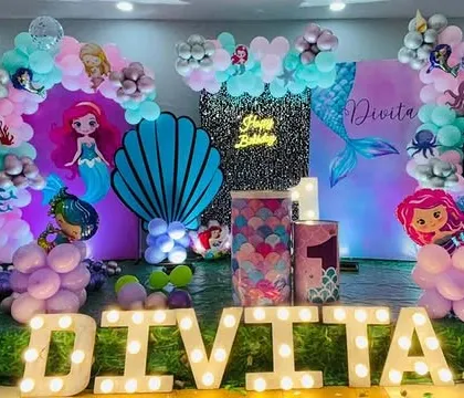 This Mermaid theme for a first birthday includes large light-up letters spelling the birthday girl's name, adding a personalized and bright touch.