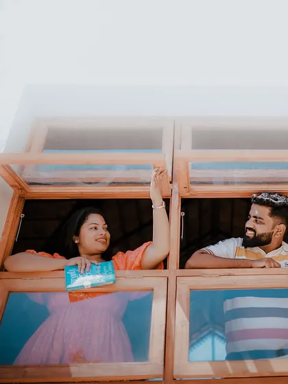 A charming photo of a couple looking at each other through adjacent windows, creating a sweet and playful connection.