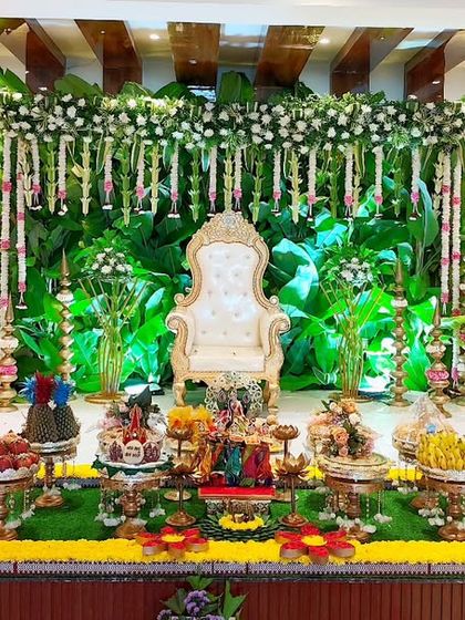 A wide view of a half-saree ceremony setup with a green and white floral theme, showing the full scale of the decoration.