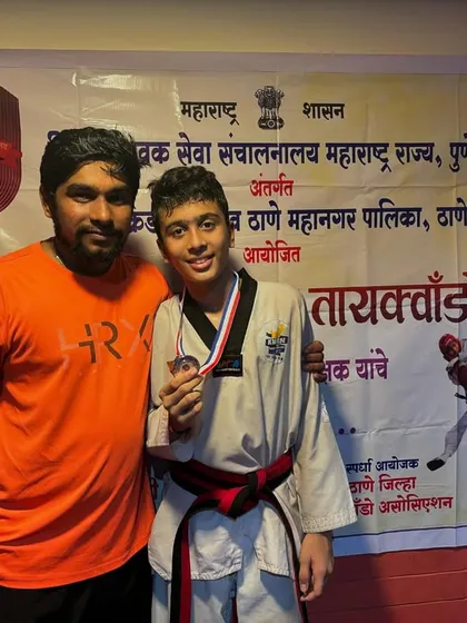 A moment of pride with a student after his win. His hard work in sparring and Poomsae practice sessions led to this victory.