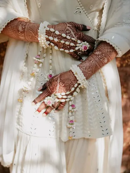 A detail shot of the bride's hands, adorned with beautiful floral jewelry that complements her ivory sharara set. It's these small touches that complete the look.