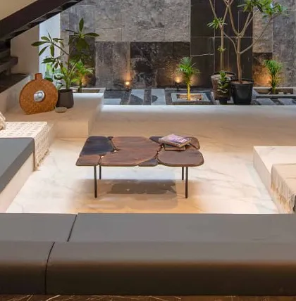 An indoor courtyard within the sunken lounge, featuring planters integrated into the floor and a live-edge wood coffee table. This design blurs the line between indoor and outdoor living.