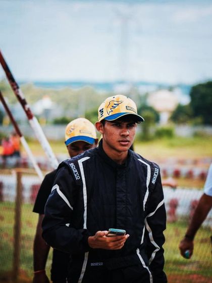 A driver walking through the pits, focused.
