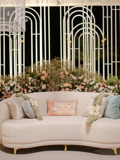 A chic lounge area with a backdrop of white wire mesh arches, softened by a lush base of pastel florals. This is how I blend modern industrial materials with romantic wedding decor.