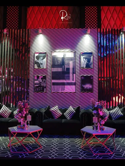 A chic lounge area for a cocktail party, with black tufted sofas, geometric-patterned carpets, and modern art on the walls.