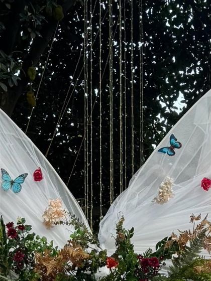 A close-up of the butterfly and floral details on the sheer fabric of the bow entrance arch. Delicate touches like these add a layer of magic and sophistication to the event design.