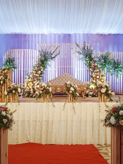A rustic yet elegant stage design with wooden panel backdrops, twin floral arches, and a vintage-style sofa, perfect for a sophisticated wedding reception.