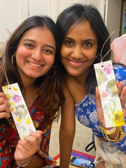 Two friends showing off the beautiful bookmarks they made by pounding fresh flowers. The smiles say it all; it's a fun, bonding experience that leaves you with a lovely, handcrafted souvenir.