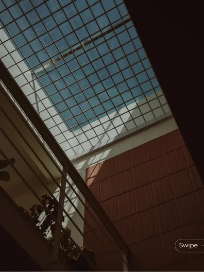 A view up towards the sky through a wire-mesh covered skylight, with the surrounding terracotta walls adding warmth to the space.