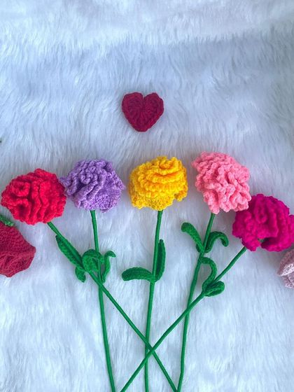 A row of single-stem crochet carnations in different colors, along with a few rosebuds. They look so pretty lined up together.