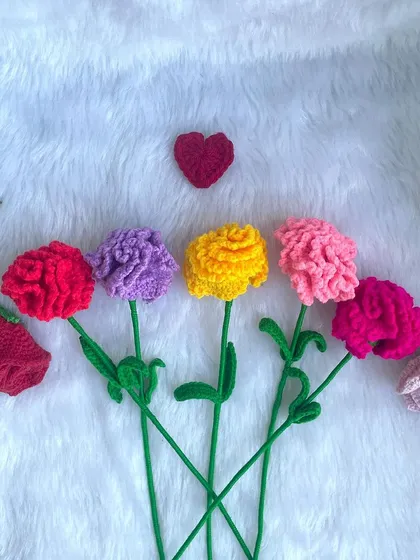A row of single-stem crochet carnations in different colors, along with a few rosebuds. They look so pretty lined up together.