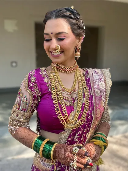A beautiful candid shot capturing the bride's happiness. The intricate details of her blouse embroidery and jewelry are clearly visible.