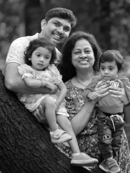 A timeless black and white portrait of a family enjoying a moment together by a tree. This classic style emphasizes the emotion and connection in the photograph.