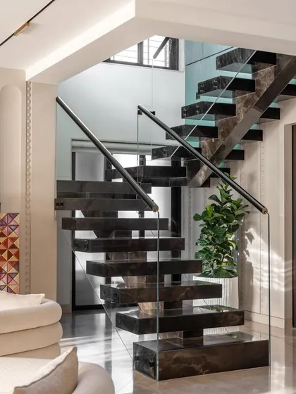 A closer view of the floating marble staircase, highlighting the clean lines of the glass railing and the rich texture of the marble steps. It's a masterpiece of engineering and design.